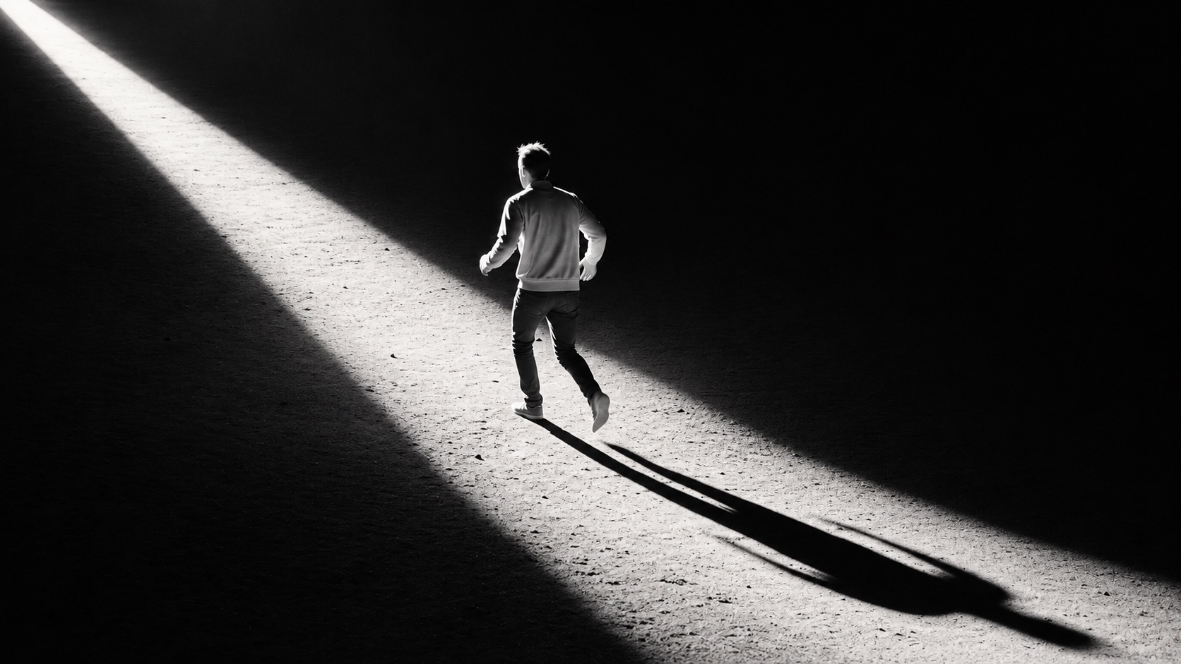 Una persona de espaldas camina por una franja de luz entre sombras